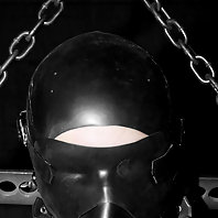 Sara Faye locked in steel bondage cage with rubber hood play.